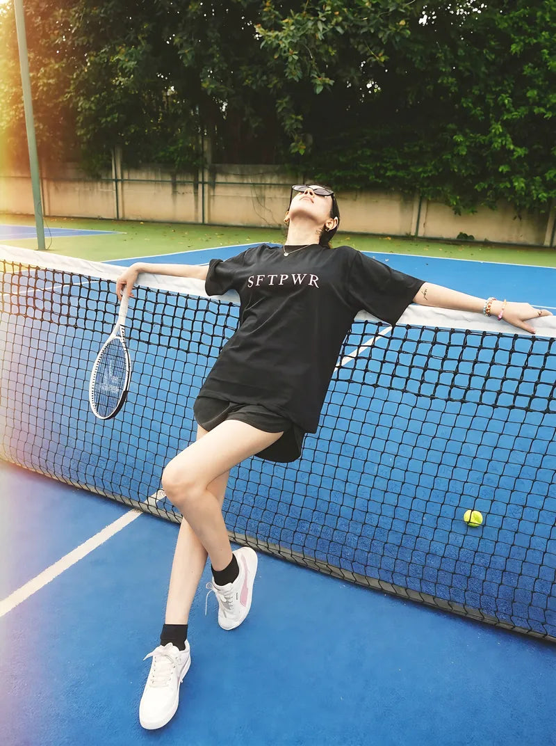 Reaching across the net in the black tee