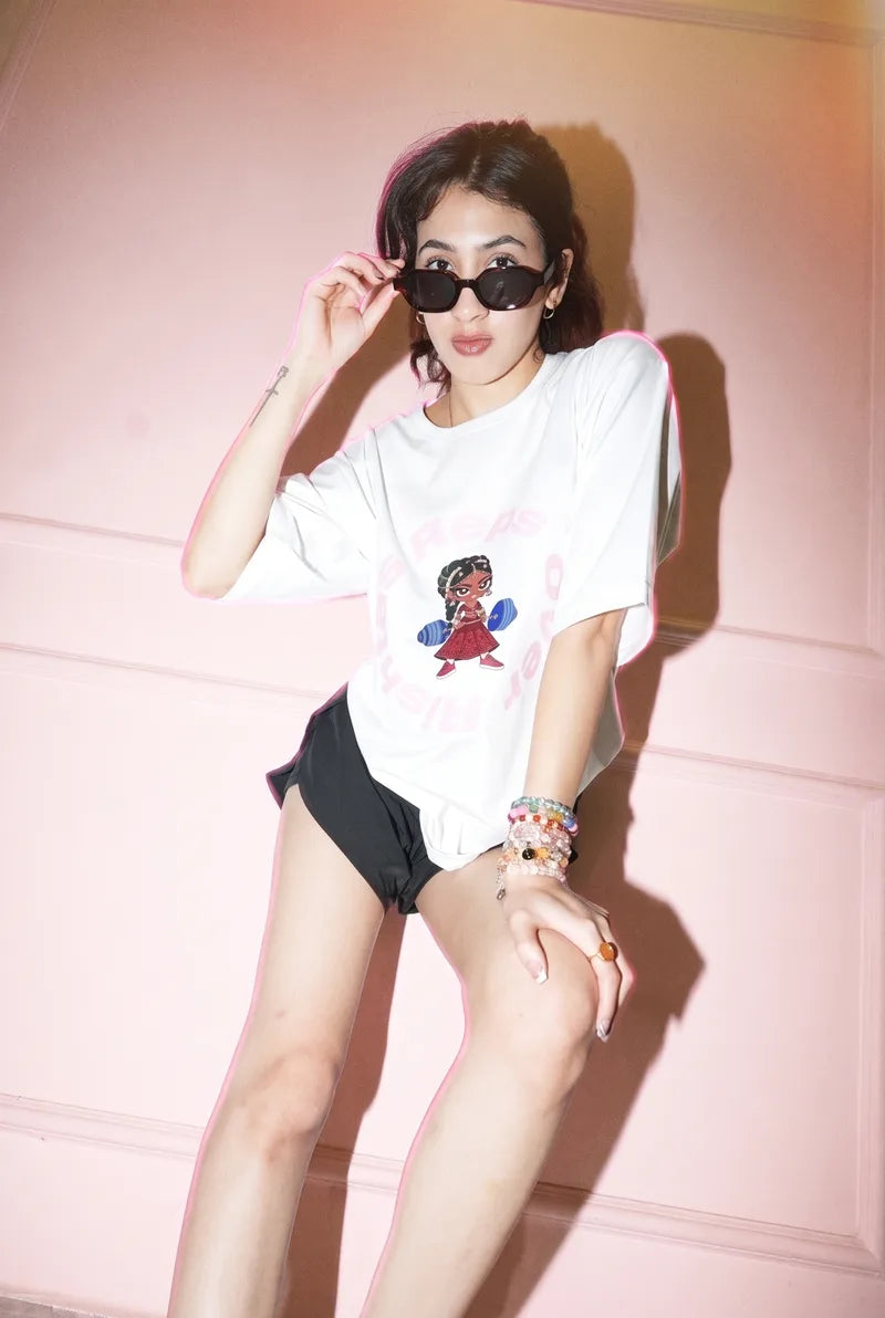 Peering over her sunglasses in the Chalk Reps Over Rishtas tee